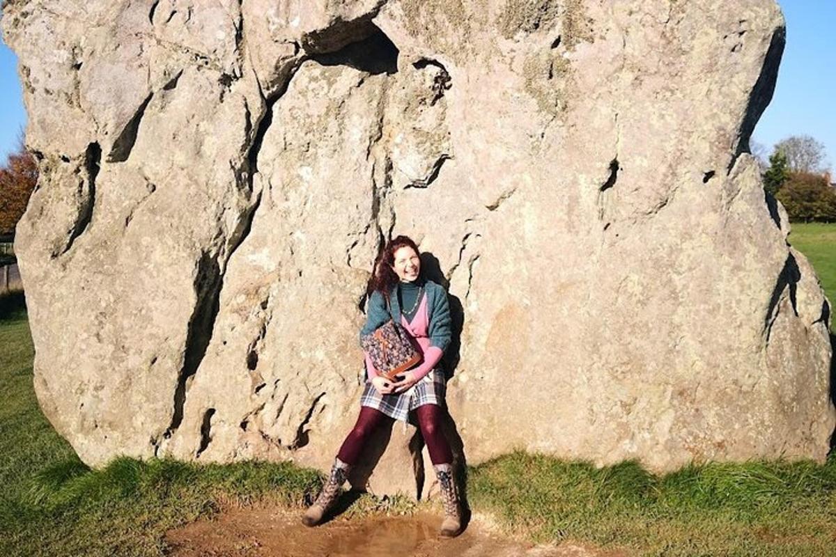 eine Frau steht vor einem großen Felsen