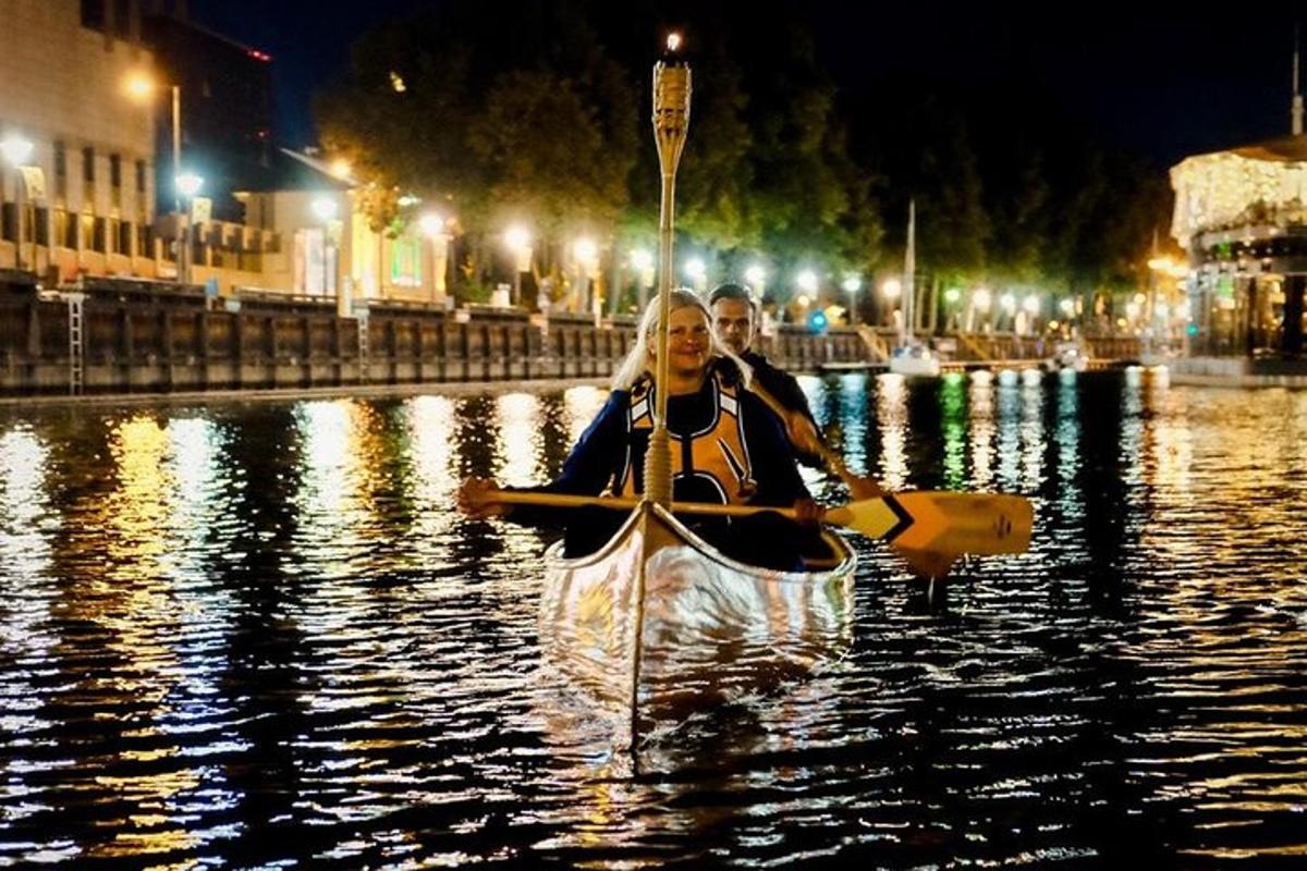 a man and a woman in a kayak in the water at night