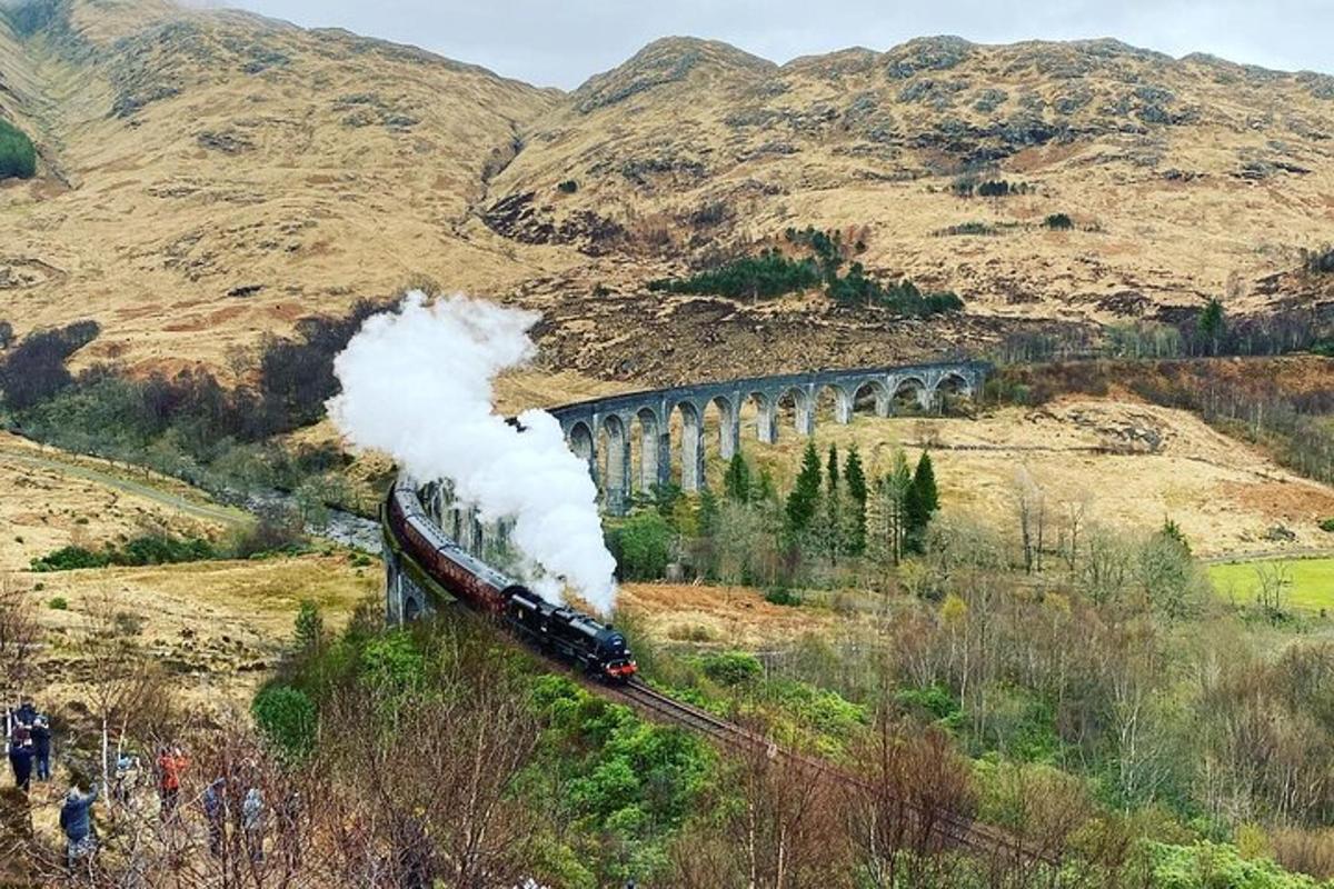a train with smoke coming out of it on a bridge