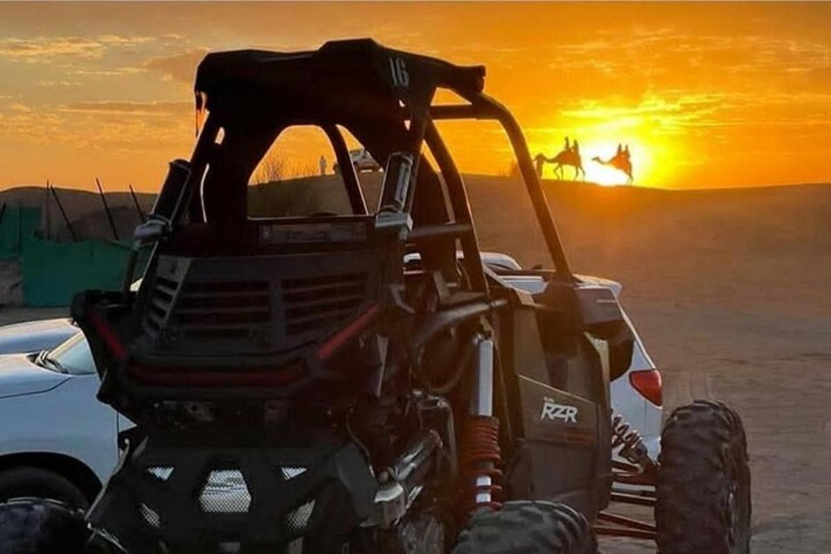 un trattore nel deserto con il tramonto sullo sfondo