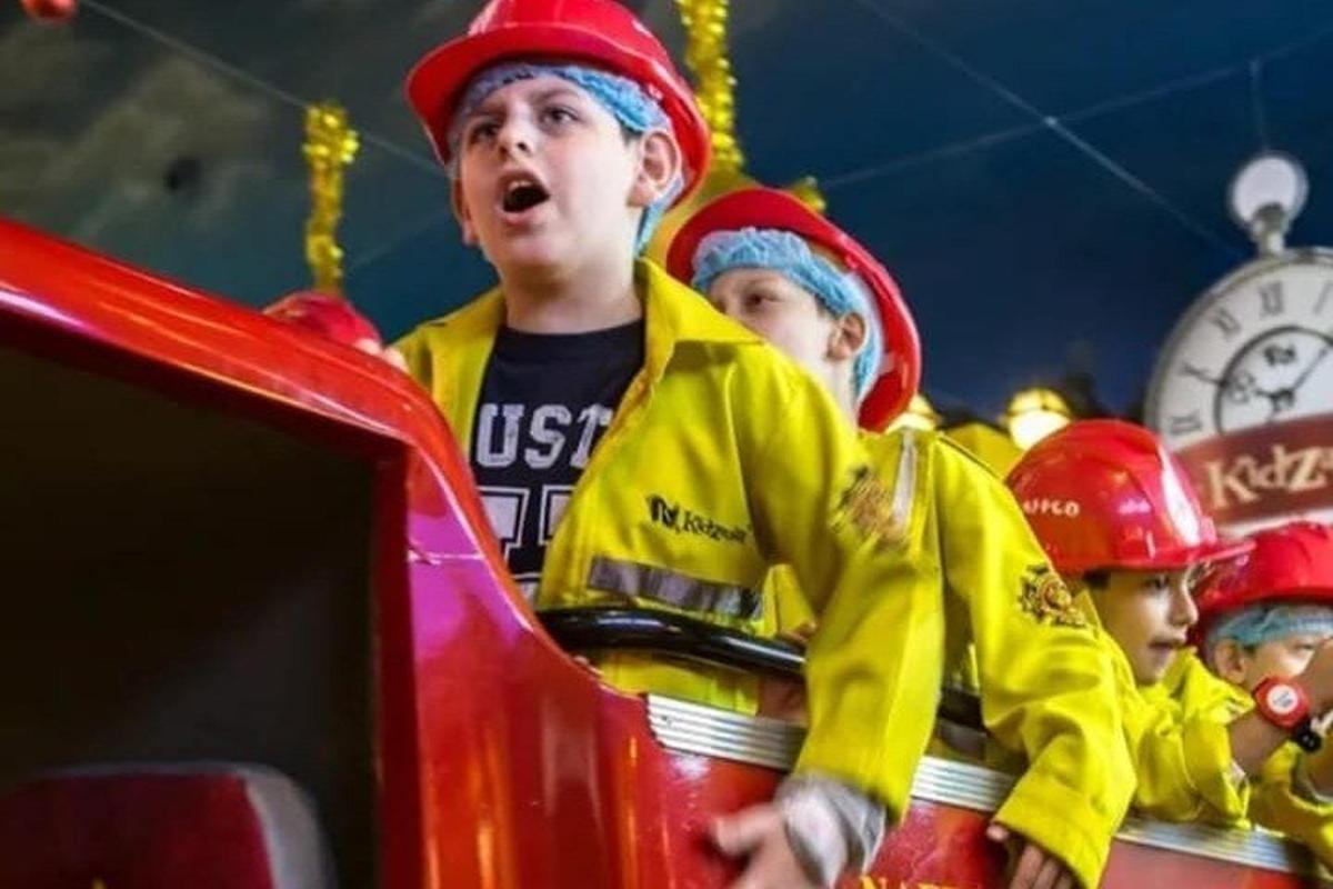 a group of children in firefighting gear standing next to a fire truck