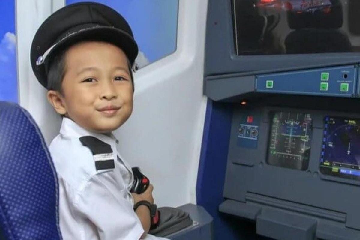 a young boy sitting in front of a machine