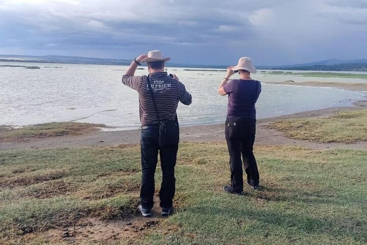 duas pessoas em pé na praia olhando para a água