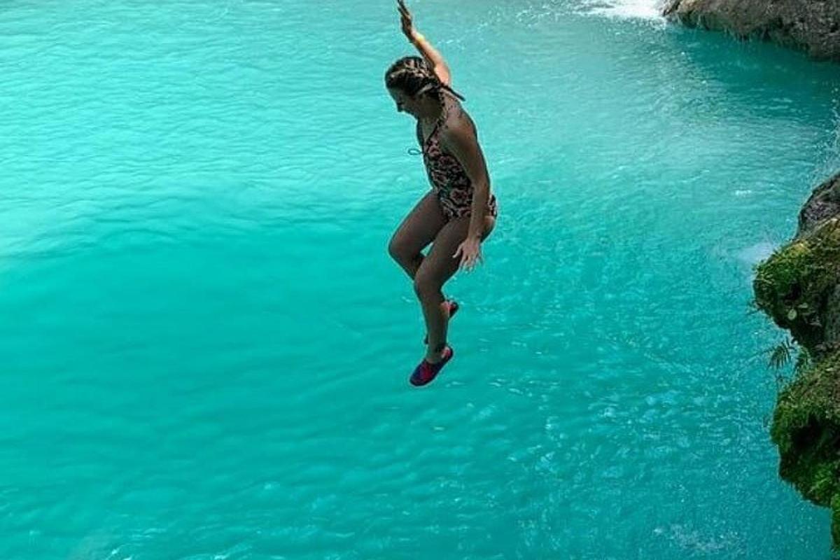una donna che salta da una scogliera in uno specchio d'acqua