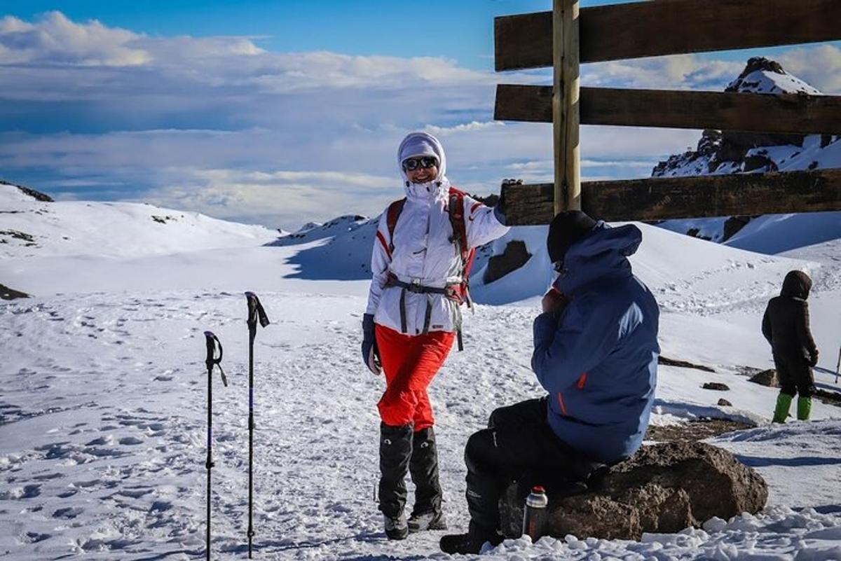 kona stendur á fjallstindi sem er þakinn snjó