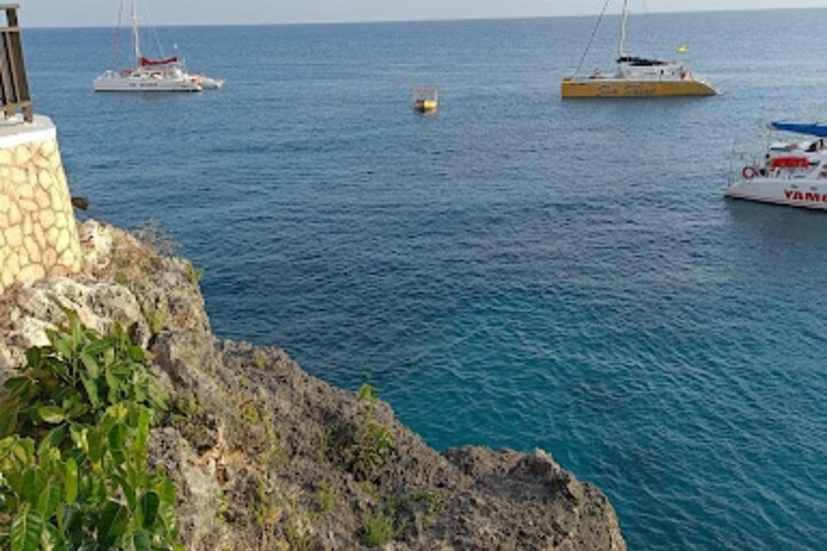 Un grupo de barcos en el agua cerca de un acantilado