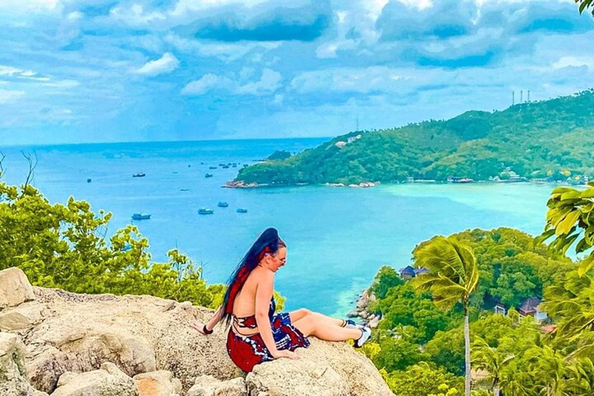 a woman sitting on a rock overlooking the ocean