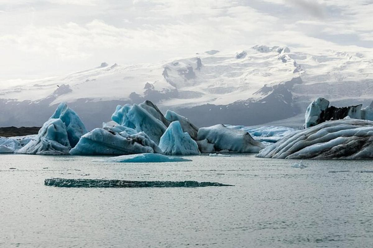 ein Haufen Eisberge im Wasser mit einem Berg