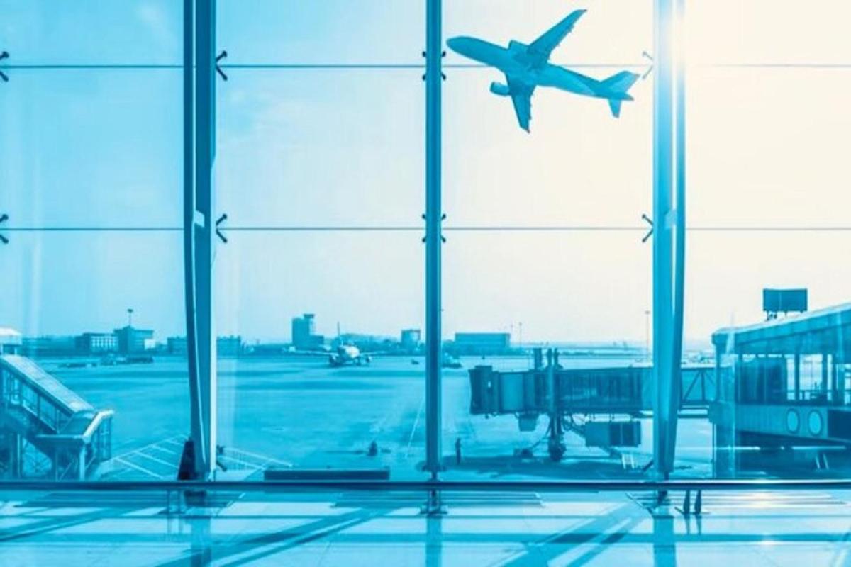 um avião está voando pela janela de um aeroporto