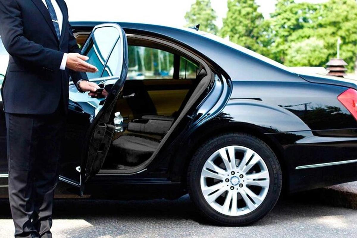 Un hombre con traje abriendo la puerta de un coche.