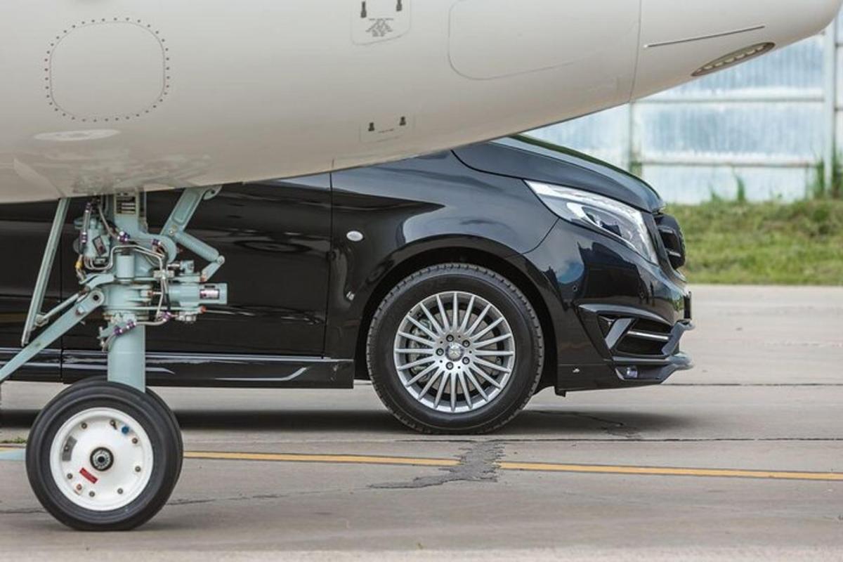 un'auto nera è parcheggiata accanto a un aereo