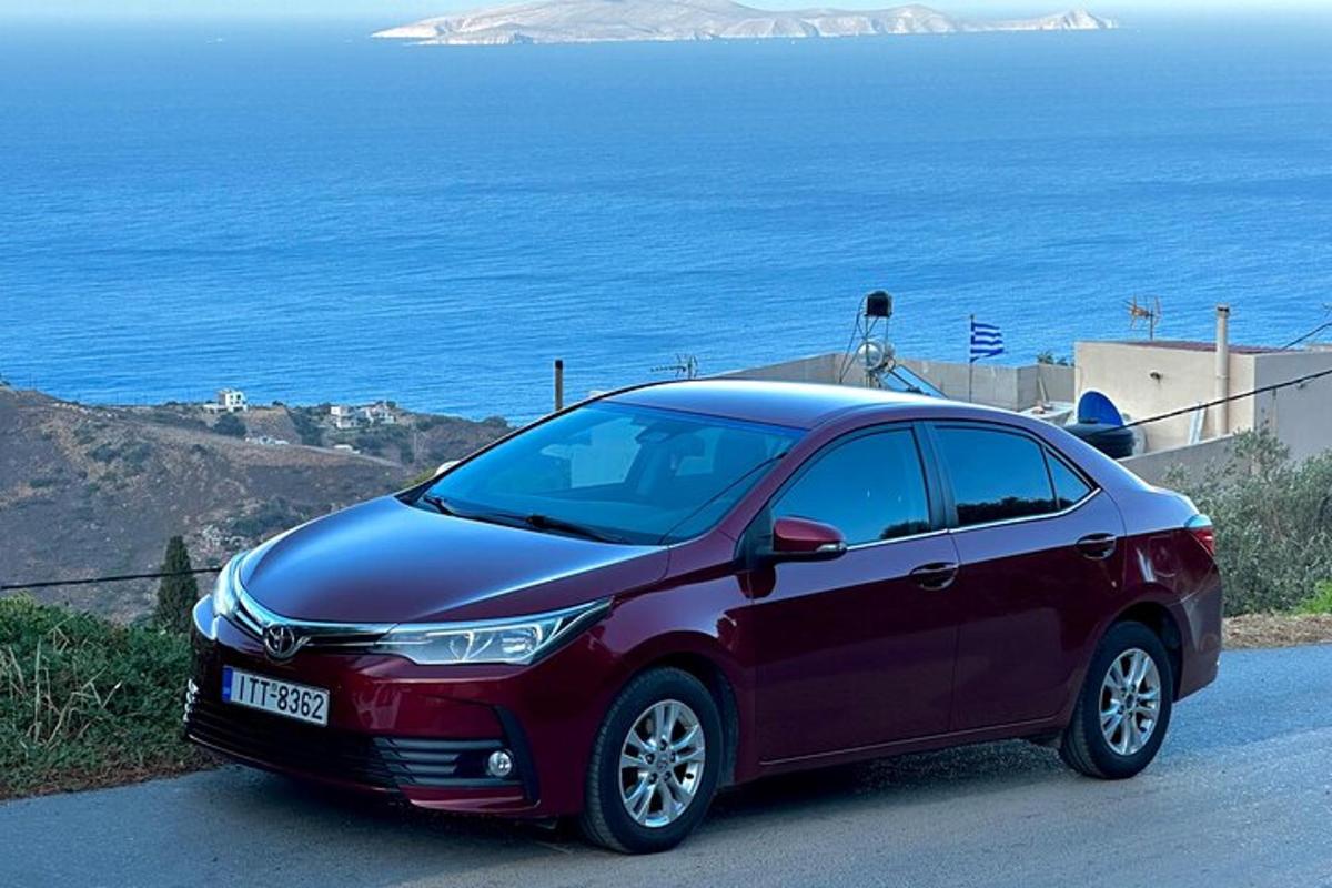 um carro vermelho estacionado em uma estrada perto do oceano