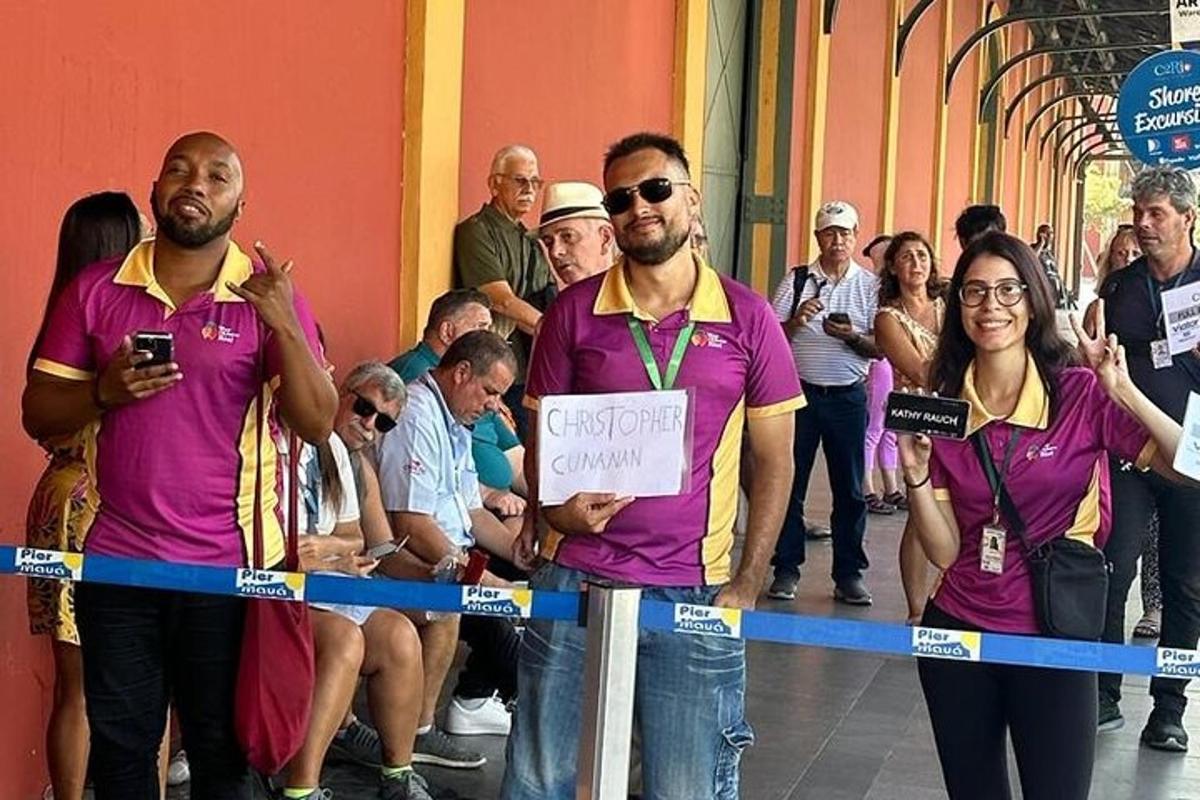 skupina ljudi v vijoličnih majicah, ki stojijo za trakom