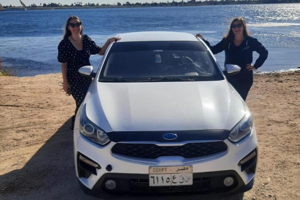 dua wanita berdiri di samping mobil putih di pantai
