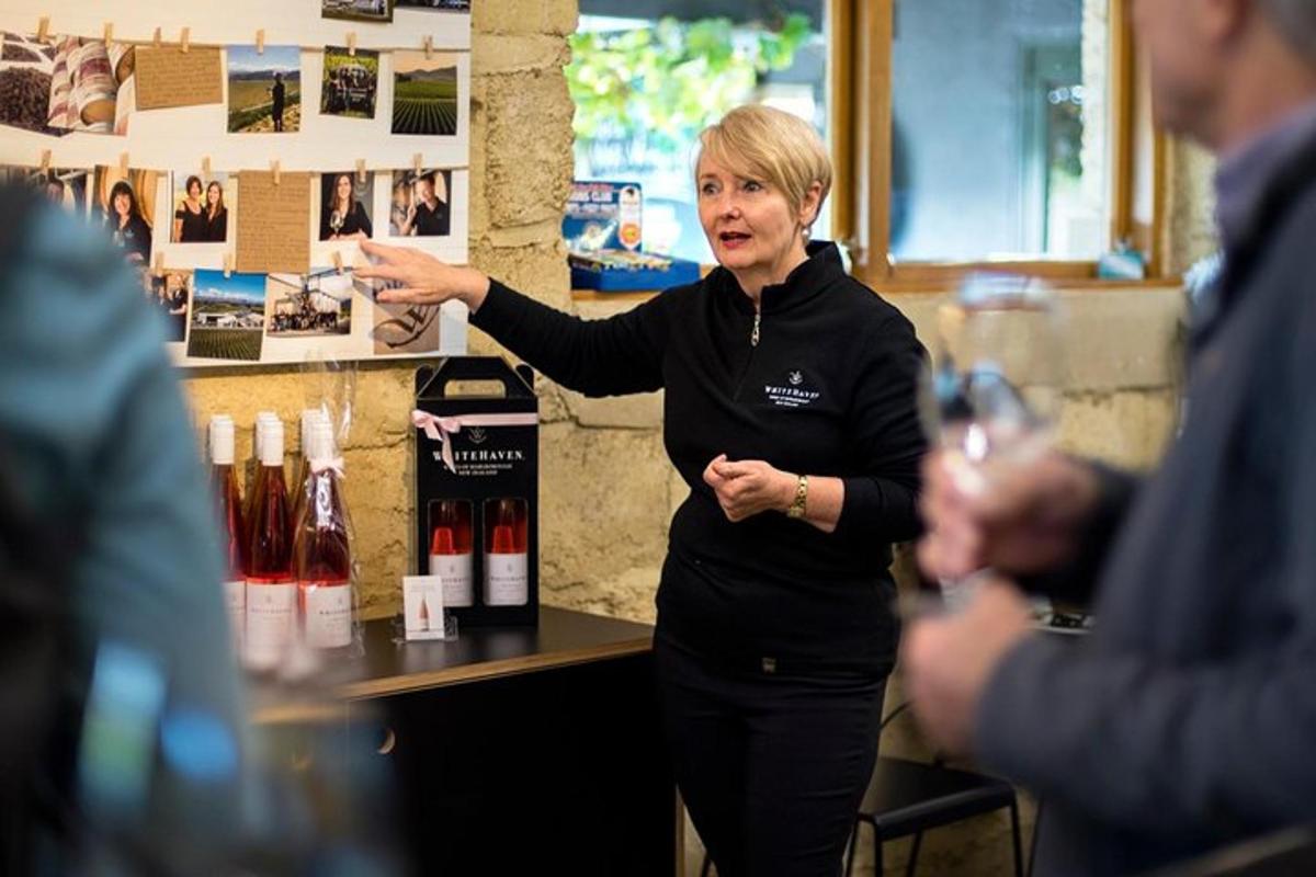 a woman standing in front of a table with wine bottles