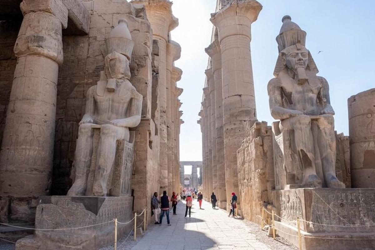 a group of people walking in front of a building with statues