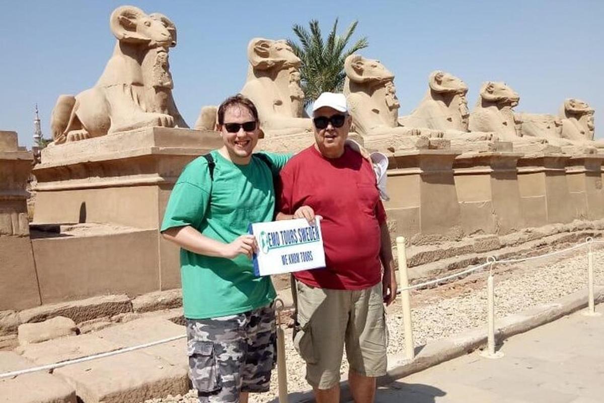dua lelaki sedang memegang papan tanda di hadapan sebuah monumen