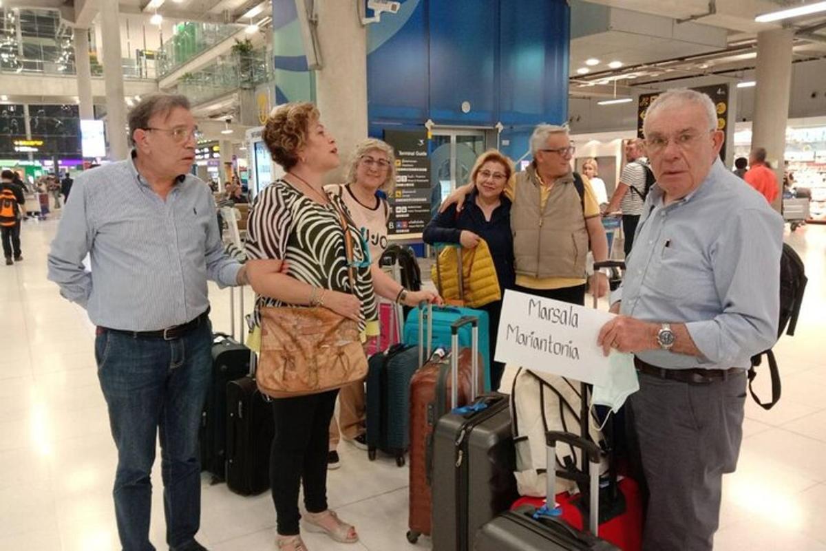 um grupo de pessoas em pé em um aeroporto com bagagem