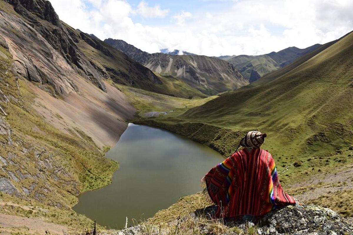 eine Person, die auf einem Berggipfel sitzt und auf einen See blickt