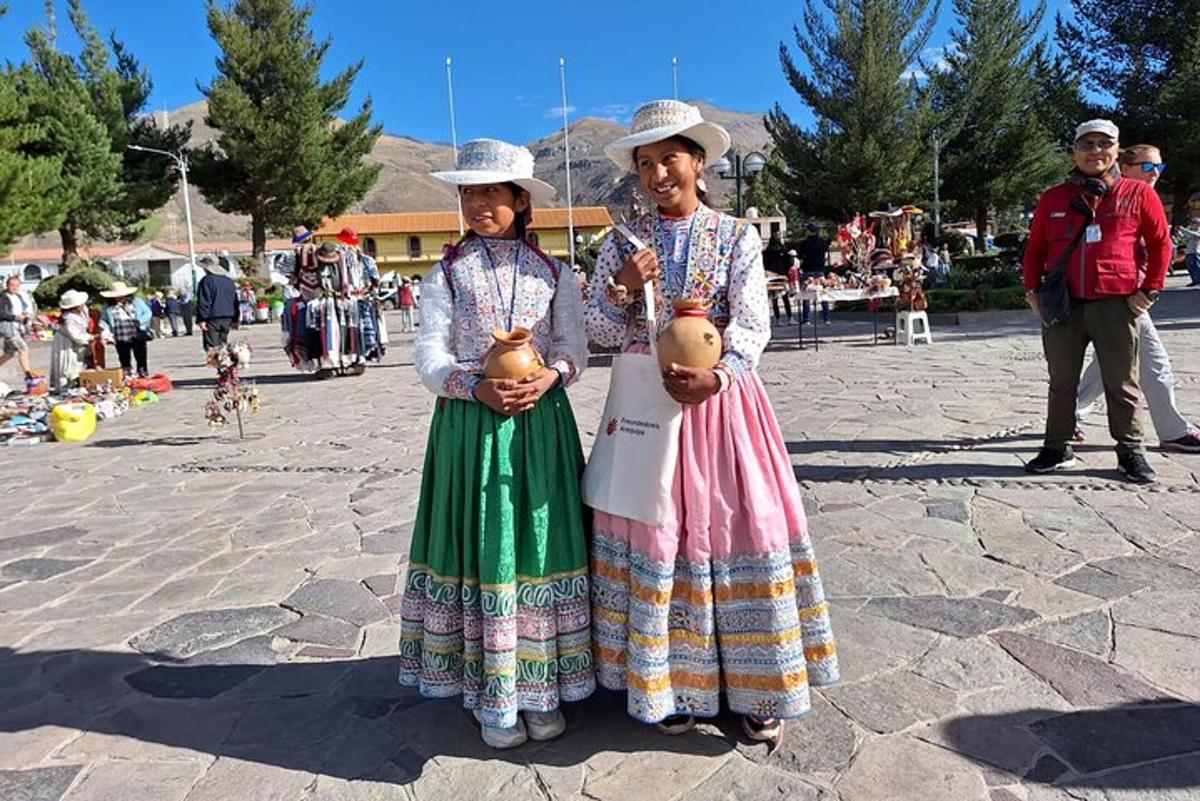 two older women standing next to each other holding statues
