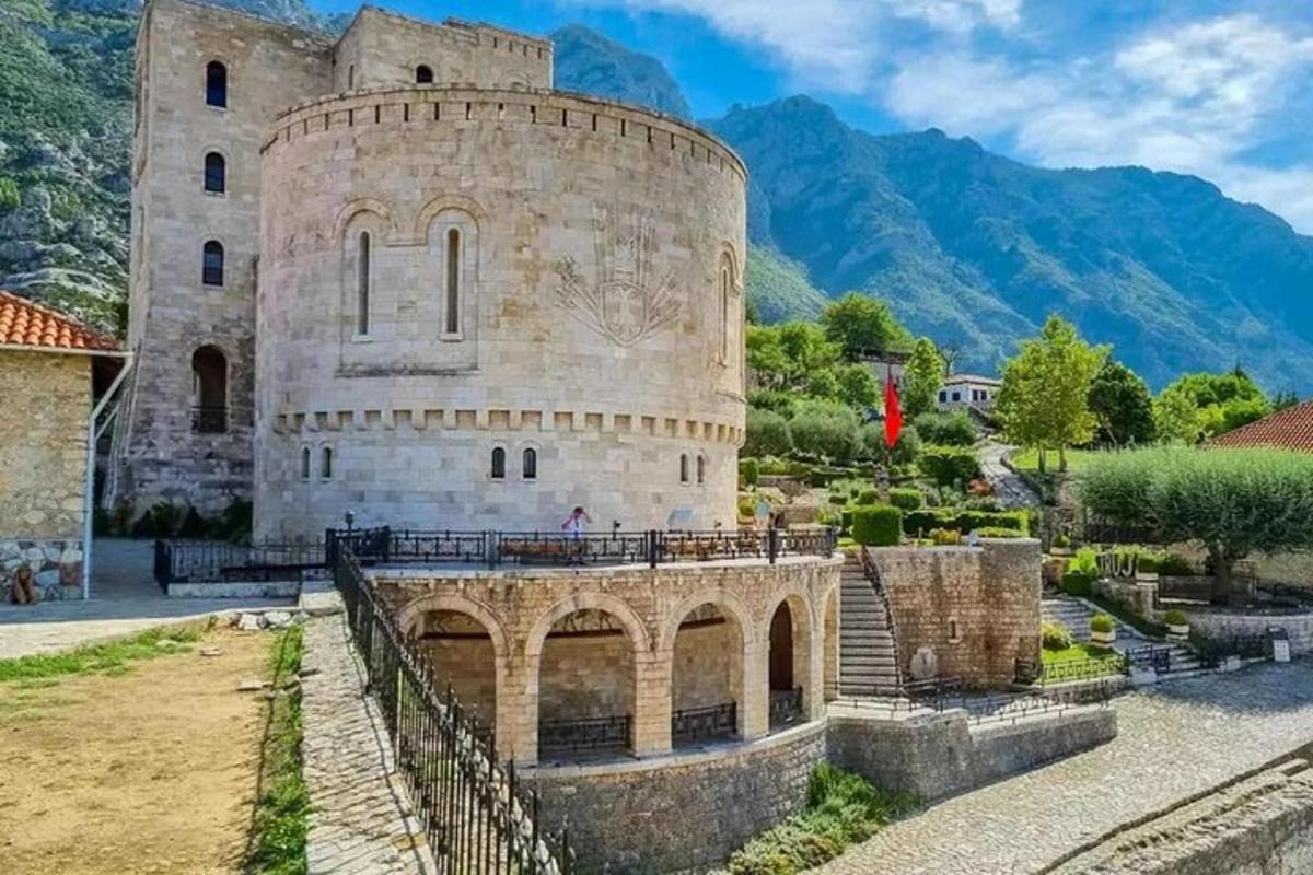 Un castillo con un puente y montañas al fondo.