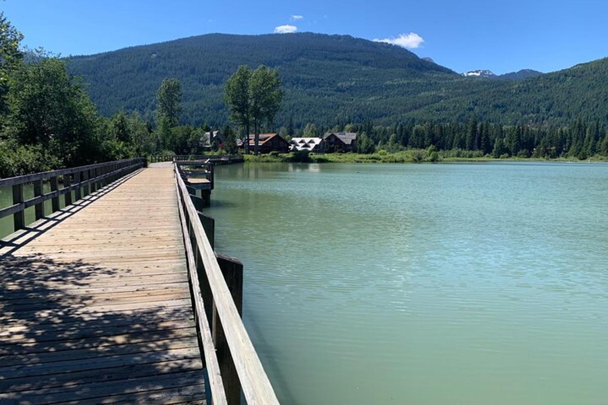 eine Holzbrücke über einen See mit Bergen im Hintergrund