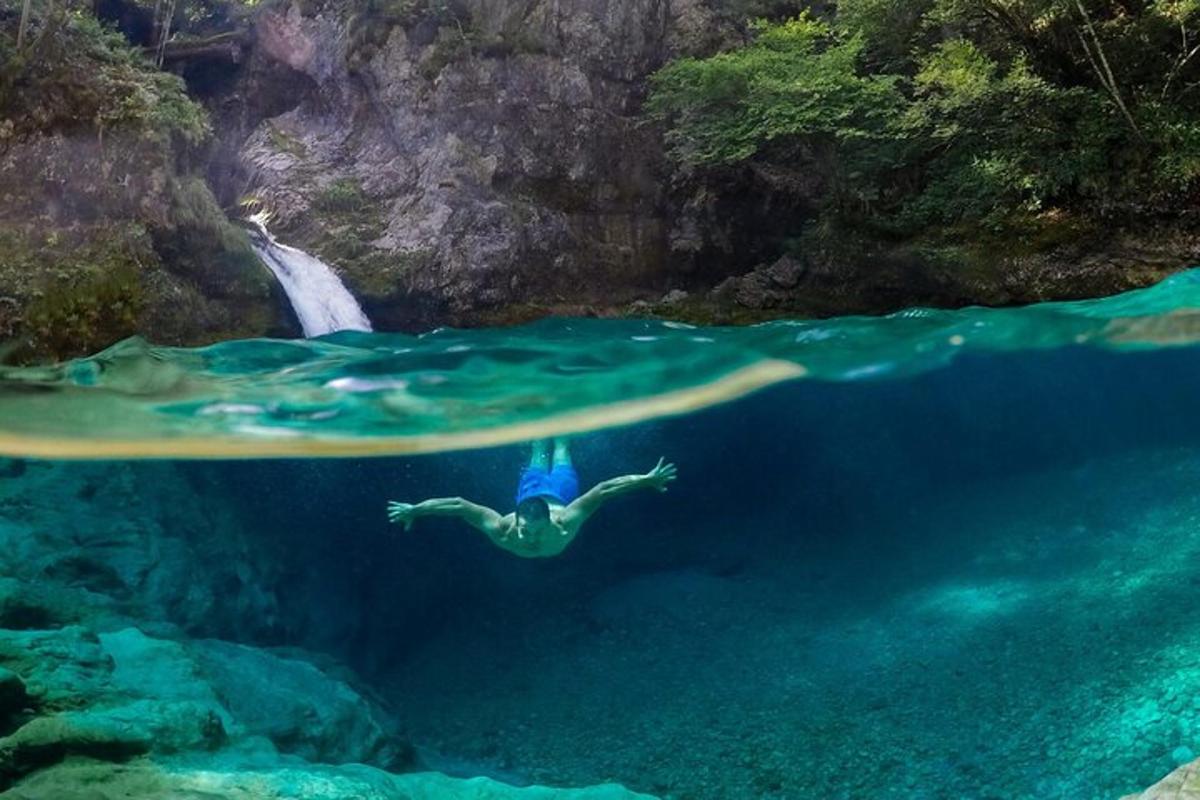 seseorang yang berenang di dalam air berhampiran air terjun