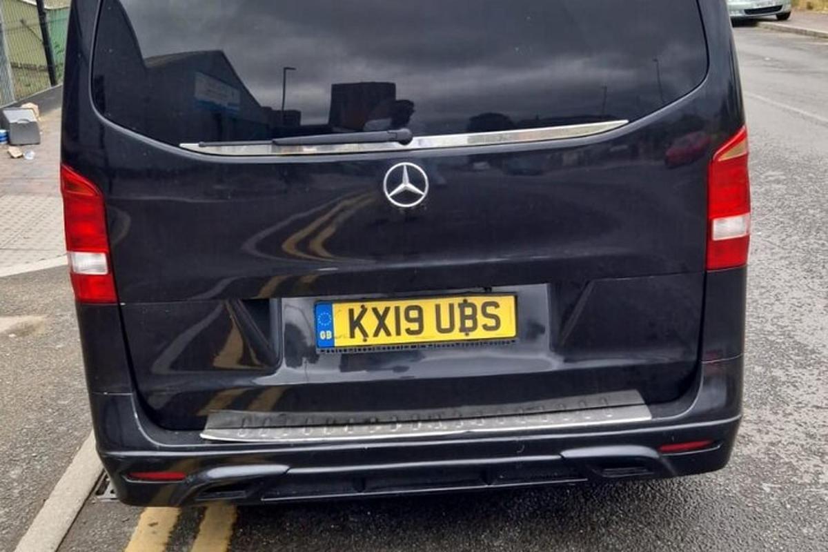 um carro preto estacionado em um estacionamento com uma placa amarela