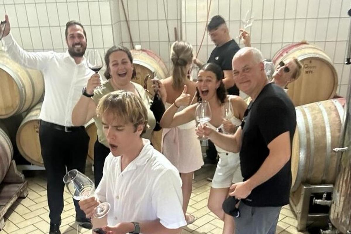 Un grupo de personas bebiendo vino en una bodega.
