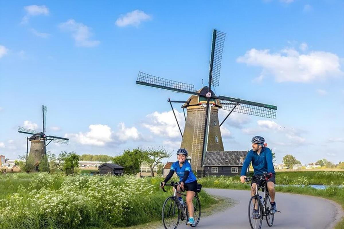 two people riding bikes in front of a windmill
