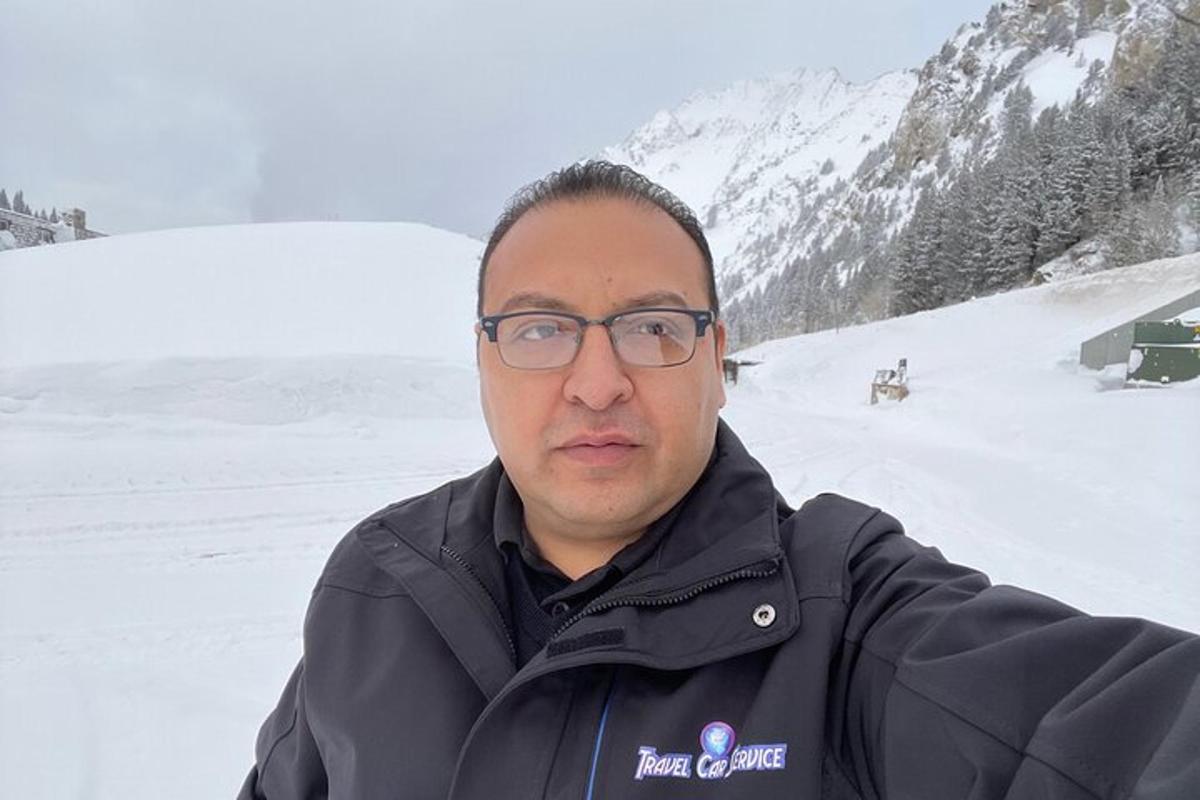 a man wearing glasses standing in the snow