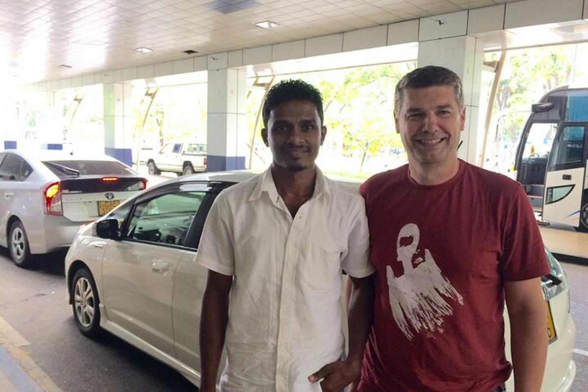two men standing in a parking lot with a car