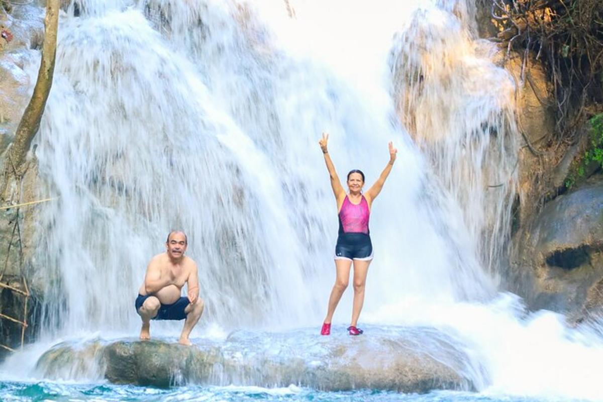 un uomo e una donna in piedi su una roccia di fronte a una cascata
