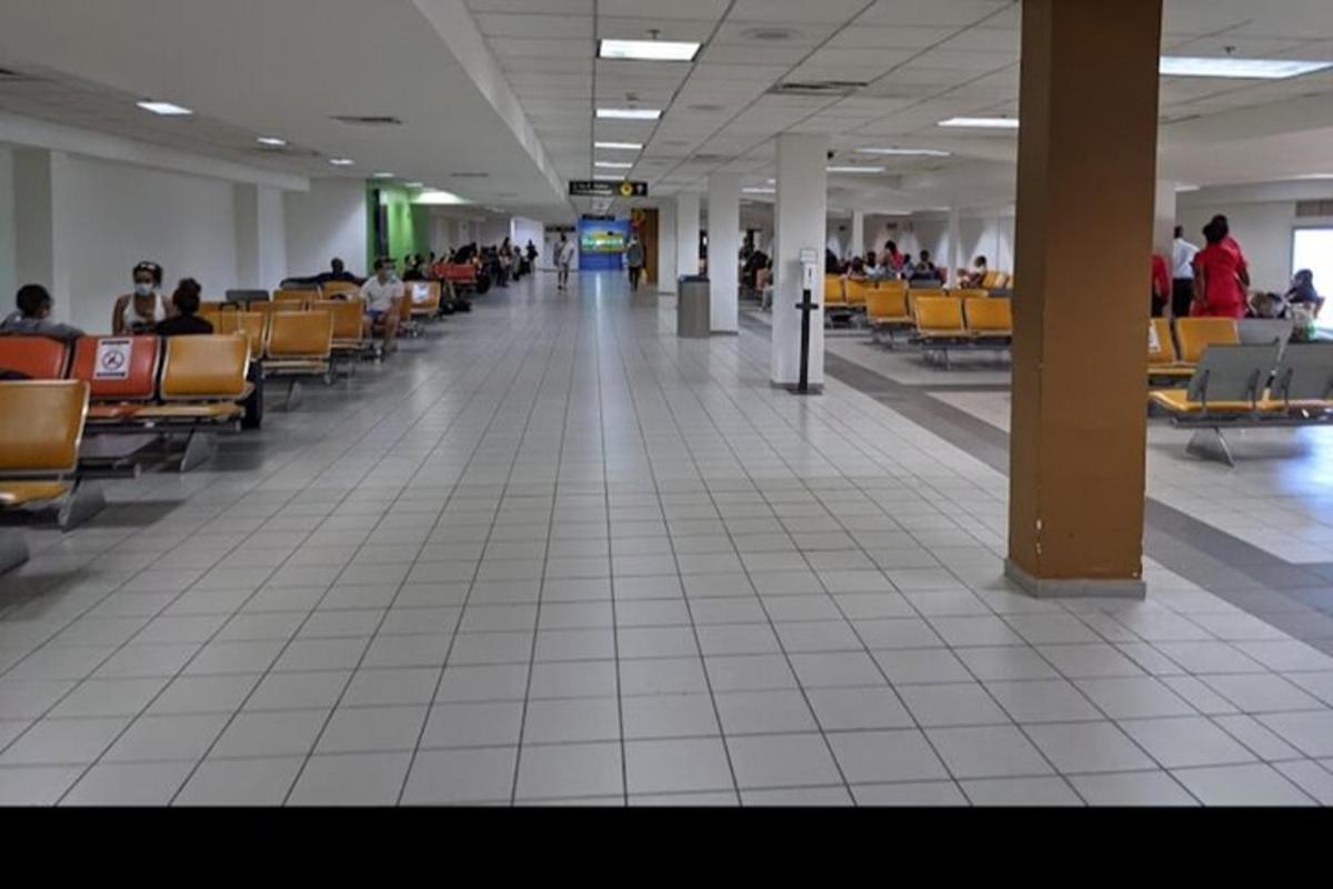 an empty hallway with people sitting in chairs in an airport