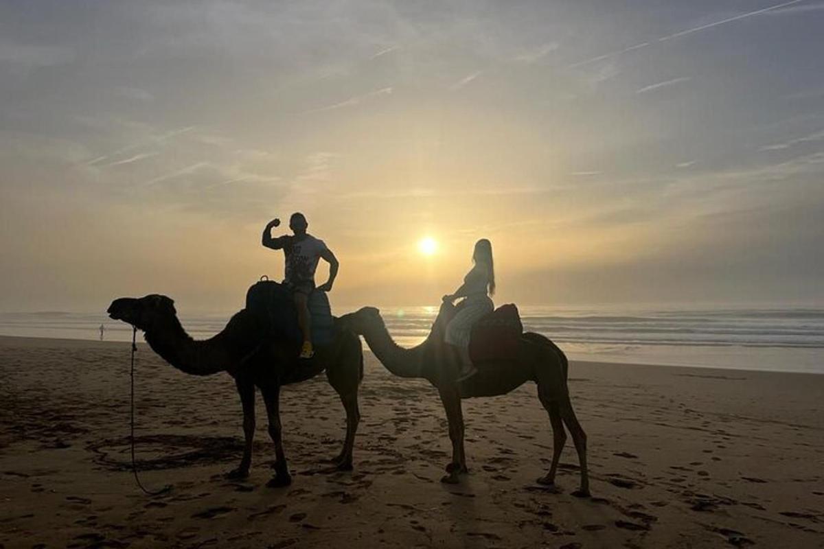twee mensen rijden op kamelen op het strand