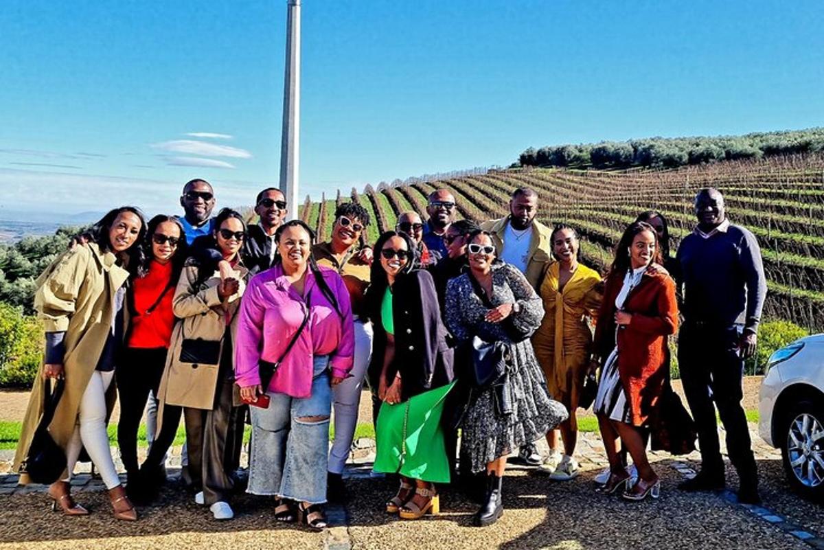 a group of people posing for a picture in front of a vineyard