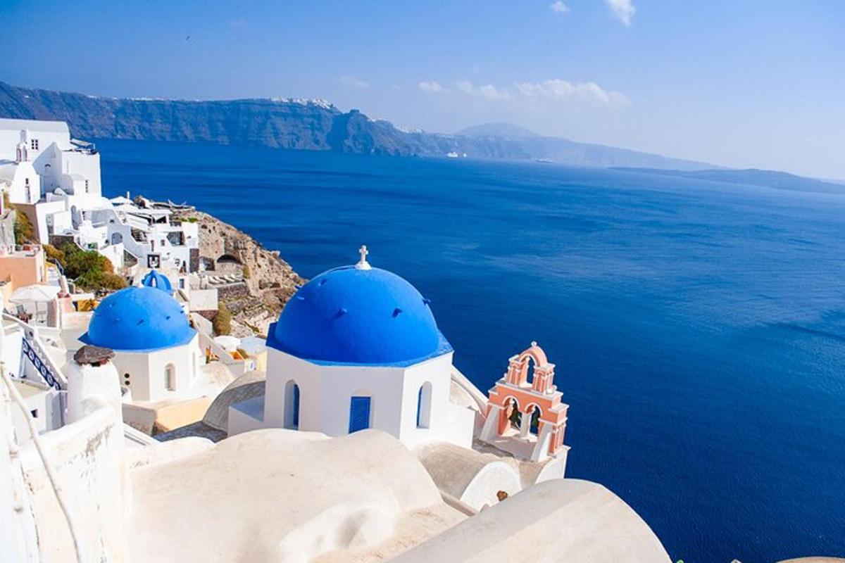 un gruppo di edifici bianchi con cupole blu e l'oceano