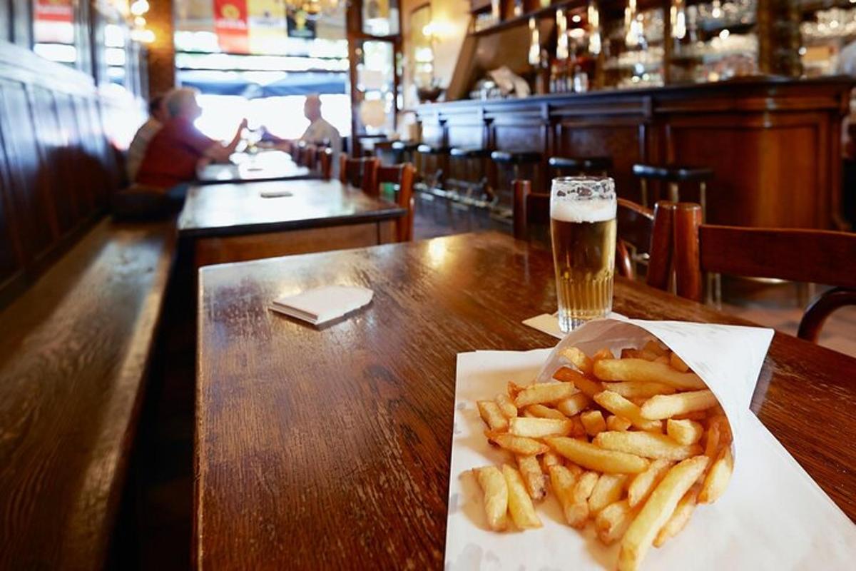 a table with a plate of french fries and a glass of beer