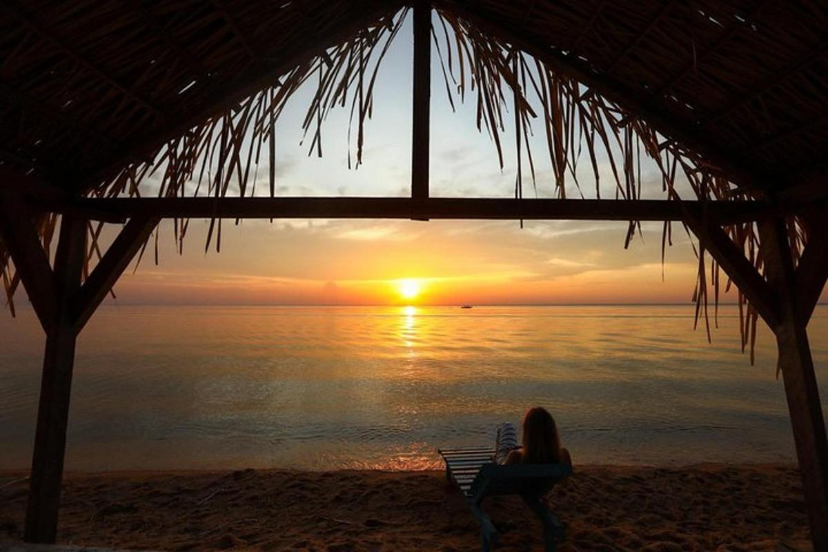 a woman sitting on a beach watching the sunset