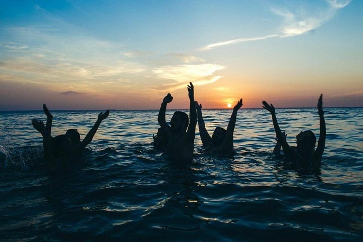 a group of people in the water at sunset