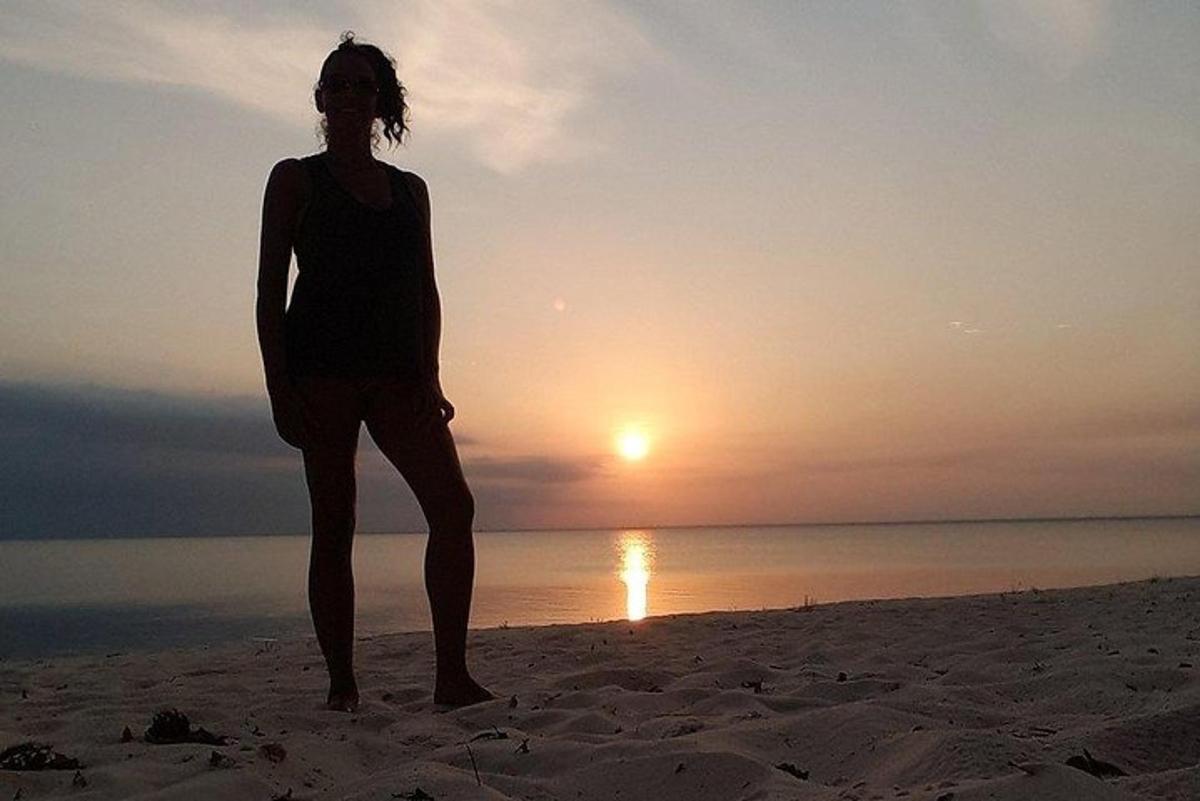 a woman standing on the beach at sunset