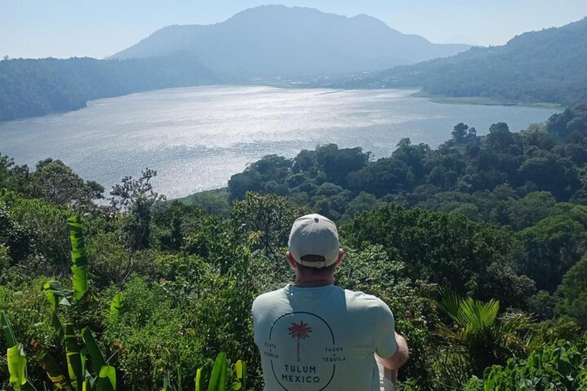 muž stojící na vrcholu kopce s výhledem na jezero