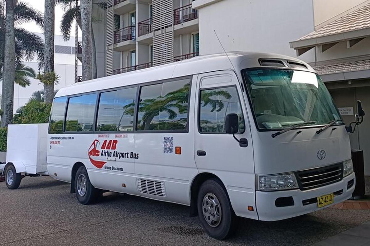 Un autobús blanco está estacionado al lado de un edificio.