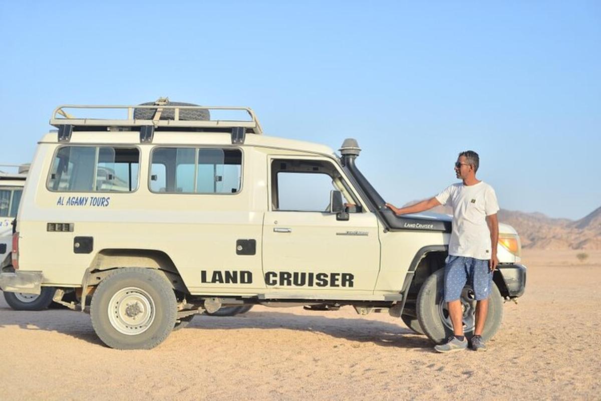 Un hombre de pie junto a un vehículo en el desierto.