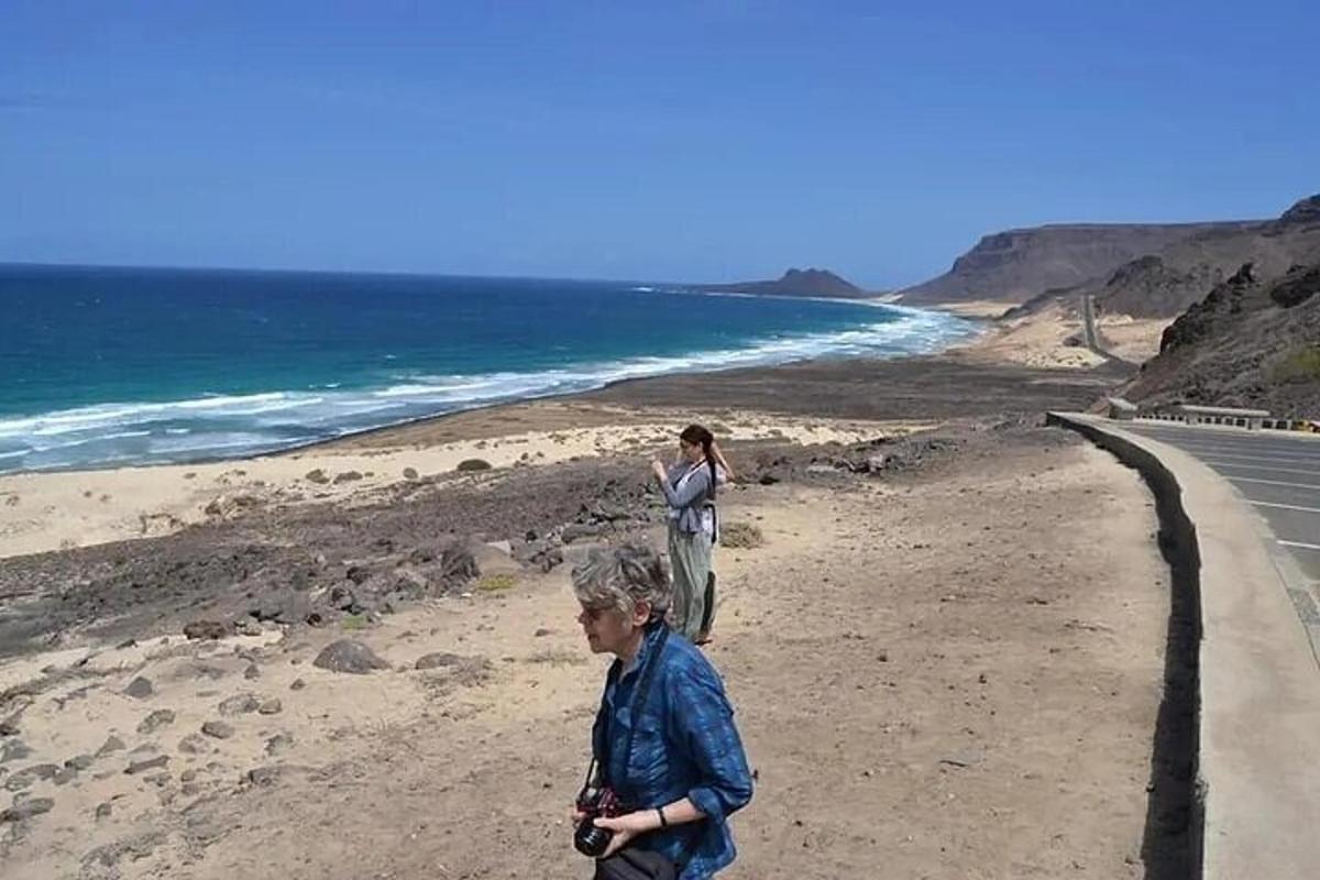 two people walking on a beach next to the ocean
