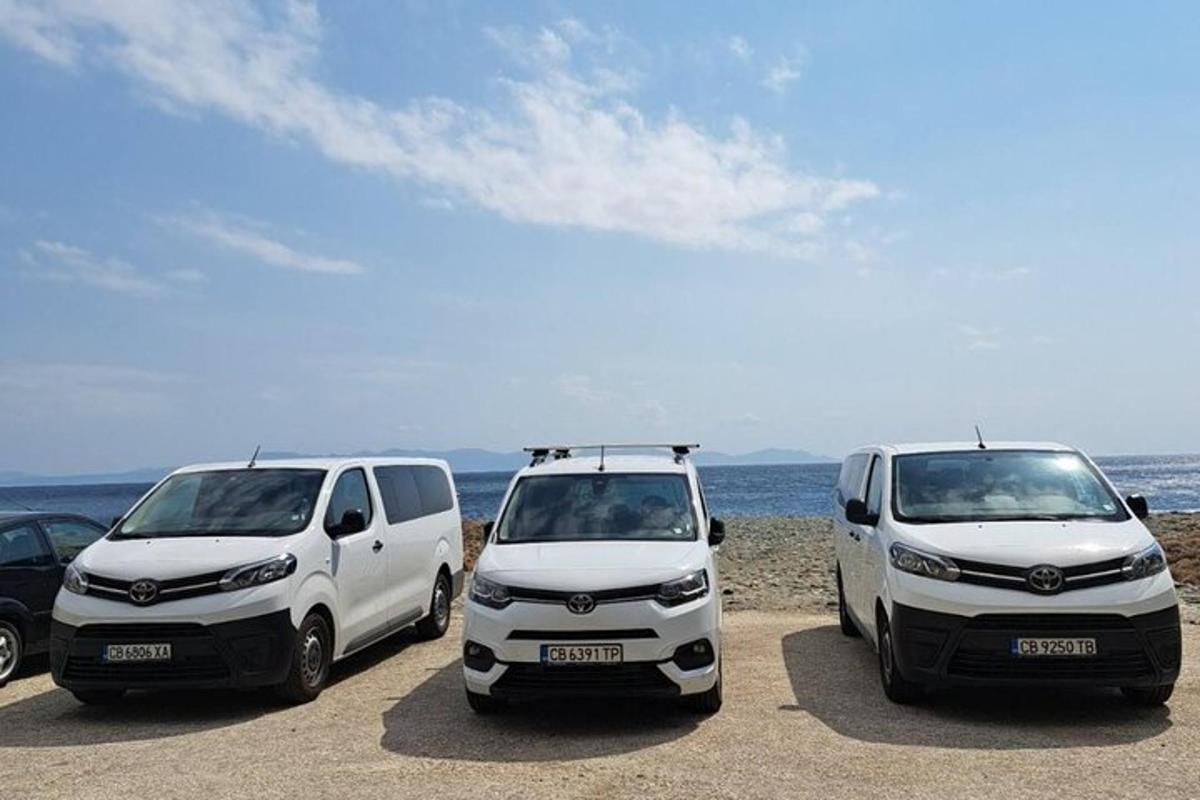 dua mobil van putih terparkir di pantai dekat laut