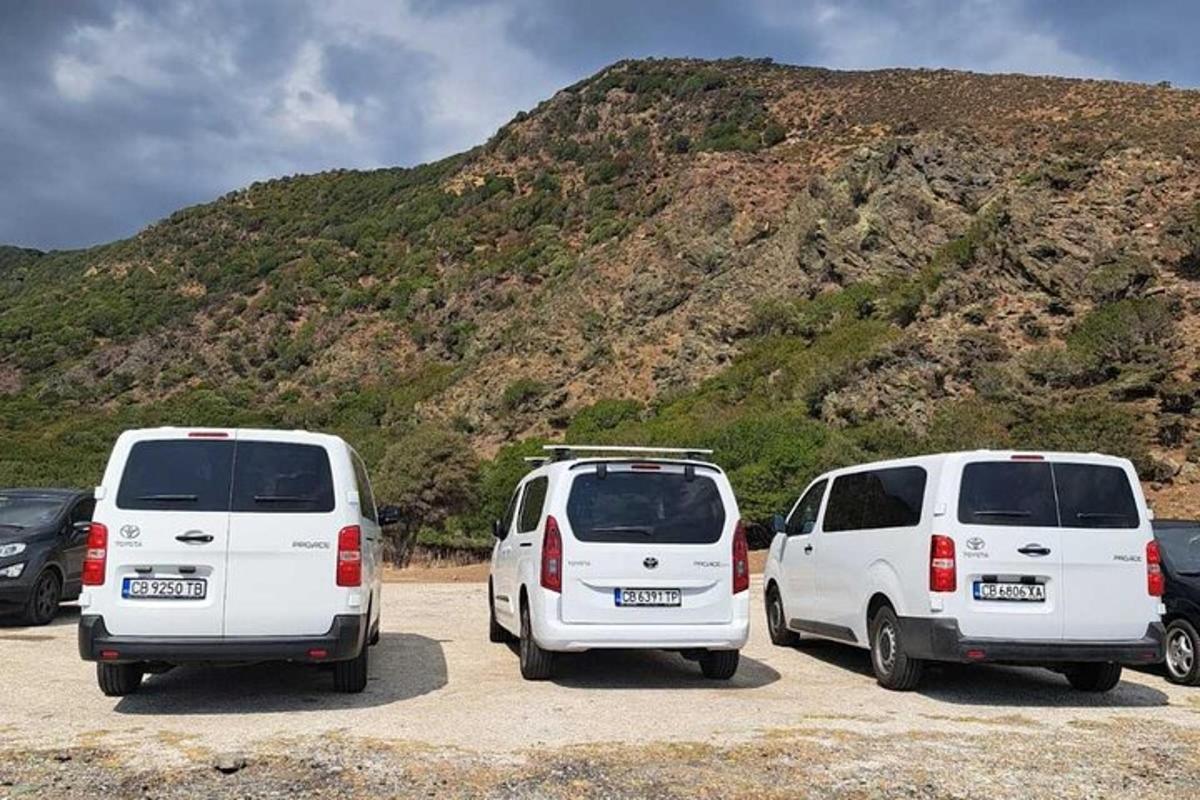 three white vans parked in a parking lot in front of a mountain
