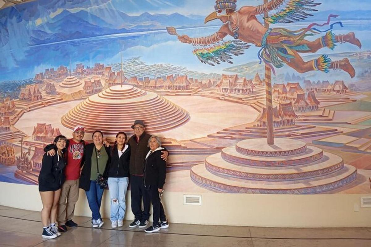 um grupo de pessoas em pé em frente a um mural