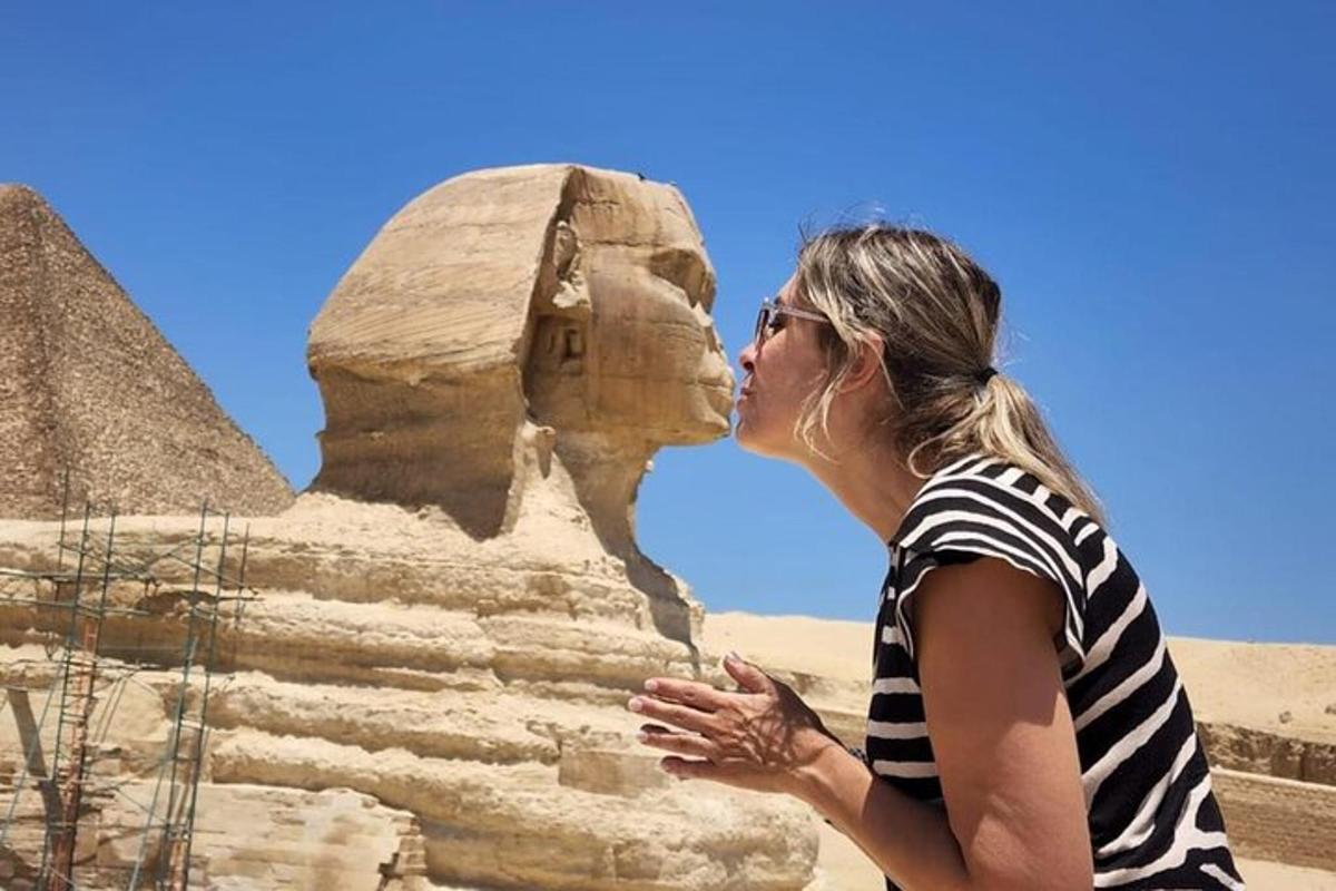 seorang wanita mencium sphinx di hadapan piramid