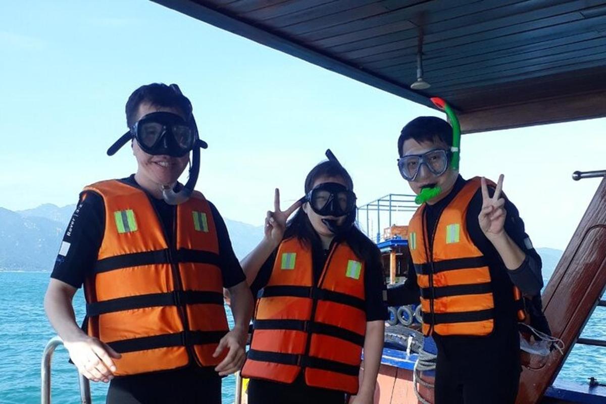 three men in orange vests standing on a boat